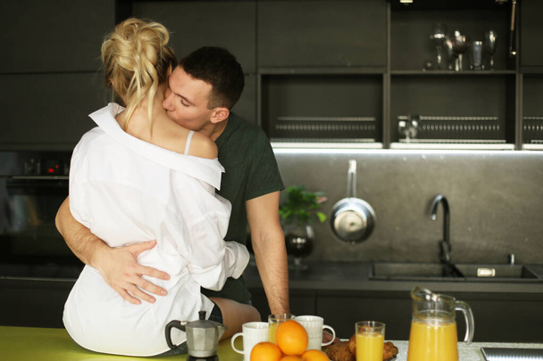 Lovely young couple standing and hugging on a kitchen at home - Foto, afbeelding