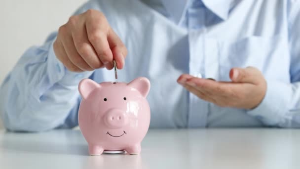 Empresaria poniendo monedas de dinero de ahorro en alcancía rosa para el concepto de inversión de fondos mutuos de finanzas y negocios - Metraje, vídeo