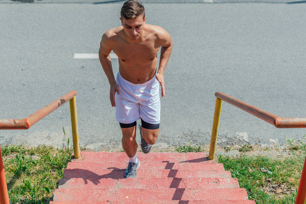 Imagen completa de un hombre caucásico sin camisa subiendo las escaleras en un caluroso día de verano - Foto, imagen