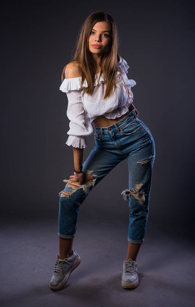 Body shot of a cool young woman wearing modern style ripped jeans - Fotografie, Obrázek