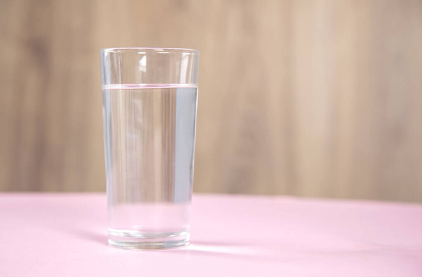 Glass of water on pink table. - Photo, image