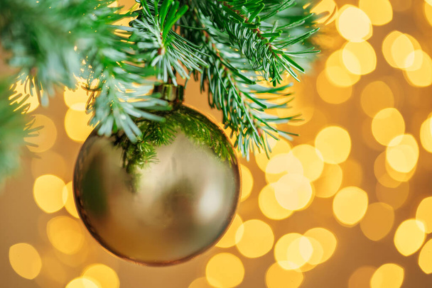 Christmas tree background with golden bauble on bokeh sparkling - Fotó, kép