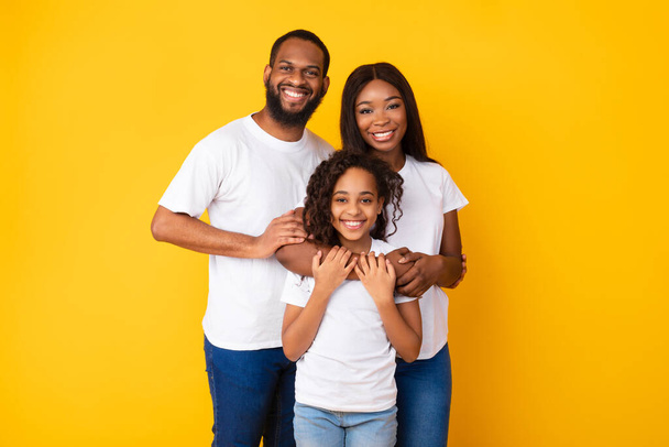 gelukkig zwart man poseren met vrouw en lachende dochter - Foto, afbeelding