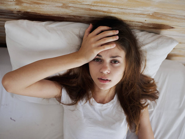 женщина держит руку на лбу температура чувствует себя нездоровым лежа в постели - Фото, изображение