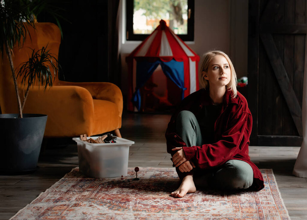 Blond woman sitting on floor at home alone  - Fotoğraf, Görsel