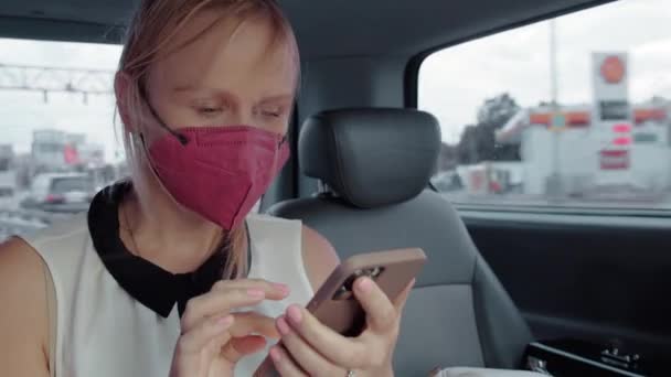 Taksideki kadın maske takıyor ve telefon kullanıyor. - Video, Çekim