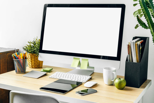 Computer monitor with mockup white screen on office table with supplies - 写真・画像