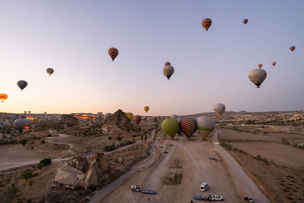 Cappadocia, Turkey - September 14, 2021: Wide angle shot of colorful hot air balloons together floating in the sky at early morning in Goreme - 写真・画像
