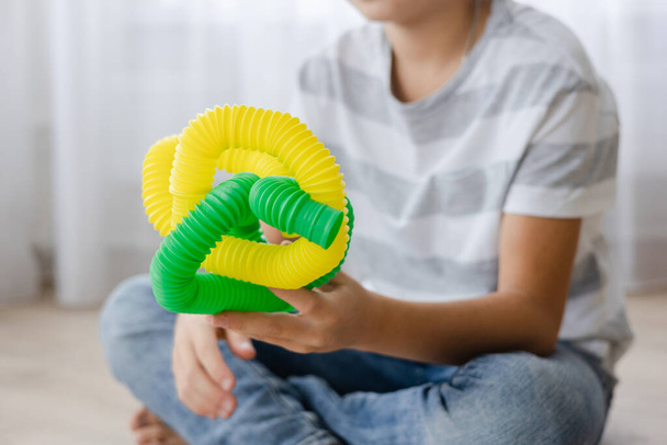 Bunte Anti-Stress-Fidget-Push-Röhrenspielzeuge für Kinder. Flexible Wellpfeife in Kinderhänden. Junge spielt mit Sinnesspielzeug. Spielspaß zur Förderung von Fantasie und Feinmotorik. - Foto, Bild