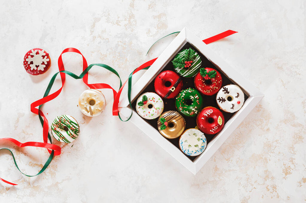 Colorful doughnuts in a gift box and beside. Christmas  Doughnuts with sugar icing  as a gift. Top view, blank space - Zdjęcie, obraz
