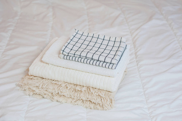 textiles de maison. Une pile de serviettes repose sur un lit blanc - Photo, image
