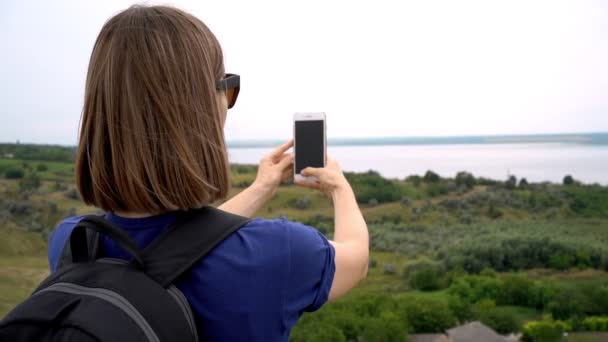 Caucasian woman with backpack, filming green landscape around her - Footage, Video