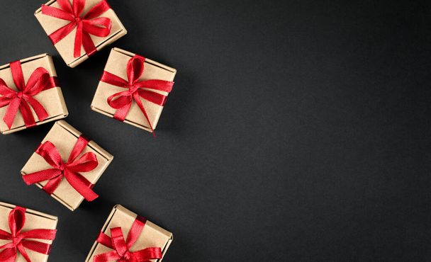braune Geschenkboxen mit roten Schleifen auf dunklem Hintergrund - Foto, Bild