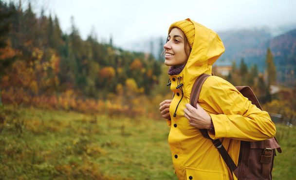Portrait hiker girl in yellow wear traveling in mountains alone, into the wild adventure - 写真・画像