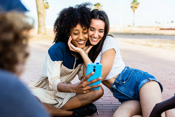 Happy multiracial women friends taking a selfie with smart phone outdoors - Photo, Image