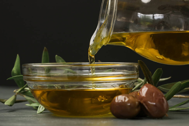 Woman pouring extra virgin olive oil in a bowl. Traditional Mediterranean homemade oil. - Photo, image
