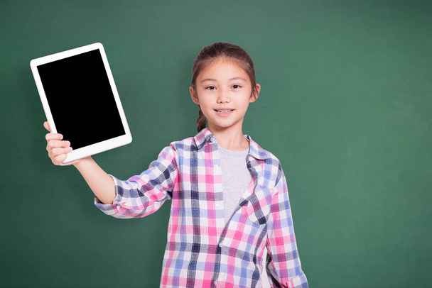 Glückliche Studentin zeigt Tablet. Isoliert auf grünem Tafelhintergrund. - Foto, Bild