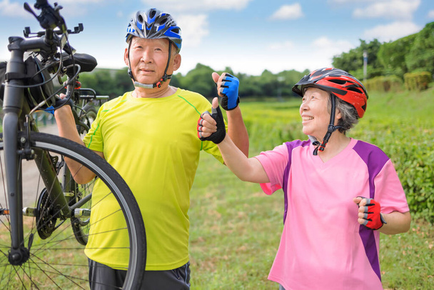 Szczęśliwa zdrowa para seniorów ćwiczy na rowerach i pokazuje kciuki do góry - Zdjęcie, obraz