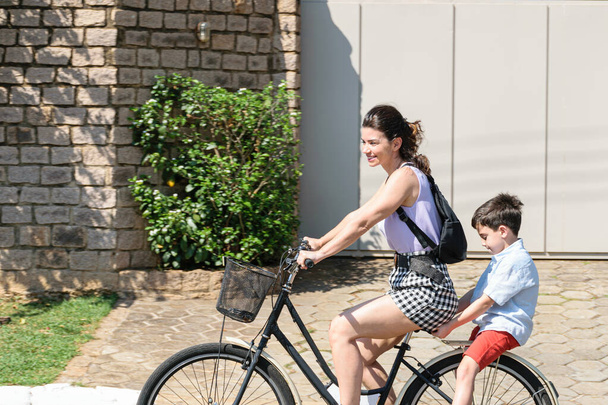 Brazilian mother and son relaxing and riding a bicycle on a sunny morning. - Photo, Image
