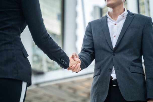 Close up of Asian young business man greeting and making handshake in the city. Partnership worker agreement is successful after complete the negotiation. Business deal, merger and acquisition concept - Photo, Image