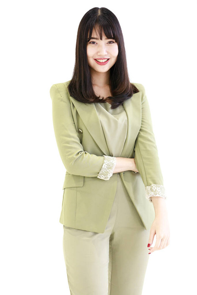 Вертикальный вид сбоку крупным планом портрет милой улыбающейся молодой азиатки в светло-зеленом костюме, смотрящей на камеру, изолированную на белом фоне. Концепция успешной предпринимательницы - Фото, изображение