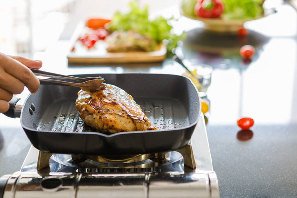 Sivukuva kokki ruoanlaitto grillattu kanan pihvi vihannesten ja kastikkeen taustalla. Valmistelu prosessi terveellistä kanasalaattia. Puhtaan ruoan ja terveellisen aamiaisen käsite - Valokuva, kuva