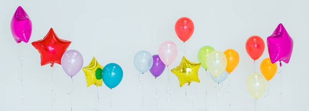 Joukko monivärinen helium ilmapalloja eri värejä kelluva vastaan harmaa tausta loman aikana juhla - Valokuva, kuva