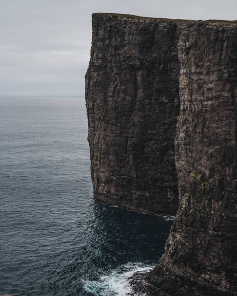 Black cliffs formation in the Atlantic ocean, Faroe Islands. Towering black cliffs on the coast of Faroe Islands - Φωτογραφία, εικόνα