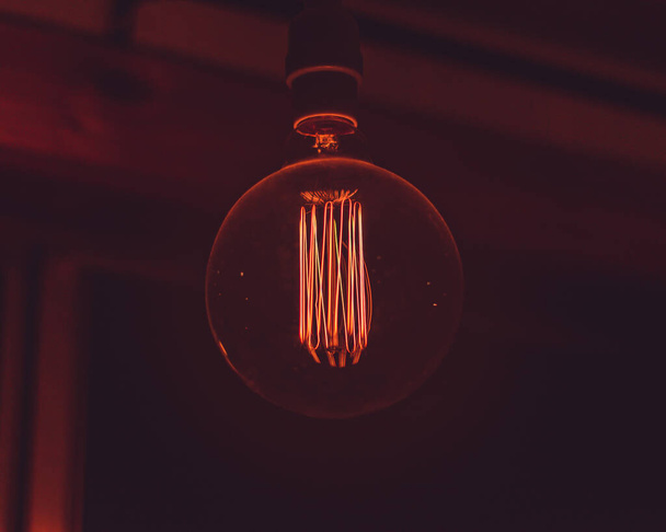 A closeup of the light bulb filament glowing in the darkness. - Φωτογραφία, εικόνα
