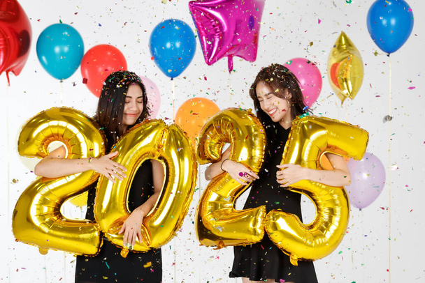 Kaksi nuorta ja kaunista seksikäs Aasian tytöt tilalla kultainen numeerinen 2025 ilmapalloja varoja ja onnea. Idea uusi vuosi juhlia puolue - Valokuva, kuva