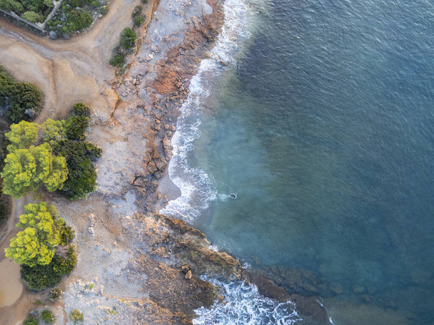 An aerial view of a rocky beach, a coastline with the waves crashing on the rocks at the seashore - Foto, Bild