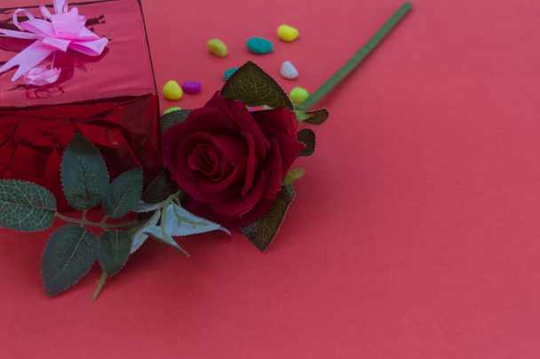 Крупним планом червона троянда розміщена на столі біля подарункової коробки з пов'язаною стрічкою на червоному тлі. Високий кут огляду. Дизайн до Дня Святого Валентина, ювілею або святкування свята прикраси
. - Фото, зображення