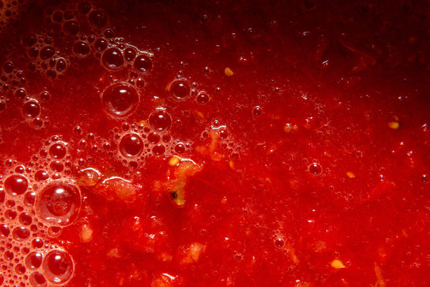 Jugo de tomate con primer plano de pulpa. En la superficie burbujas de diferentes tamaños y espuma.  - Foto, Imagen