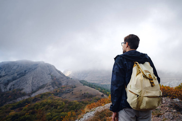 muž s batohem a hole pro pěší turistiku v horách. Začátek podzimní sezóny. Krásné mlhavé počasí - Fotografie, Obrázek