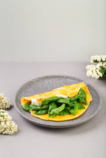 Omelette stuffed with spinach and cheese for a breakfast, with flowers on table - 写真・画像