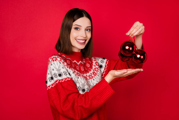 Photo of sweet pretty young woman dressed print pullover holding new year decorations isolated red color background - Fotó, kép