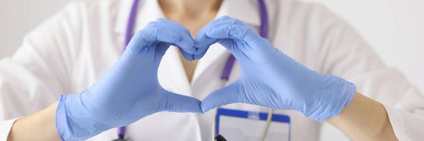 Doutor em máscara médica protetora mostra coração com as mãos - Foto, Imagem
