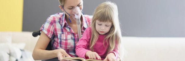 Woman in wheelchair and oxygen mask is reading book with little girl - Photo, Image