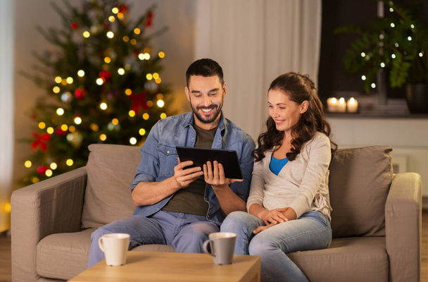 happy couple using tablet pc at home on christmas - Foto, Bild