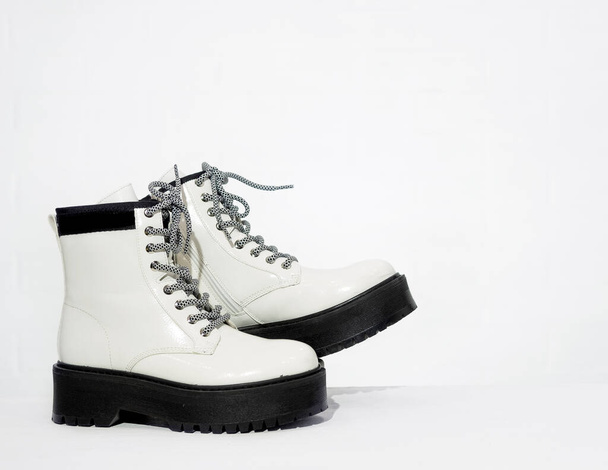 Nowe damskie skórzane białe wodoodporne jesienne buty z koronkami i masywnymi podeszwami w sklepie, modne obuwie na zimę. Zakupy online, nowa kolekcja, konsumpcjonizm, zakupy i koncepcja branży mody - Zdjęcie, obraz