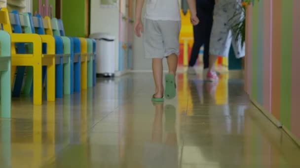 Egy fiú lábai sétáltak az óvodai folyosón. Gyermekek az óvodában. - Felvétel, videó