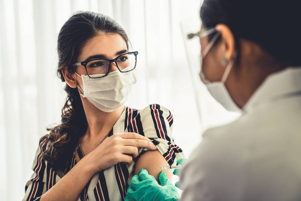 Une jeune femme consulte un médecin habile à l'hôpital pour se faire vacciner - Photo, image