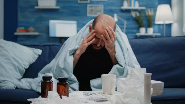 Nahaufnahme eines kranken Erwachsenen mit Kopfschmerzen, der die Schläfen reibt - Foto, Bild