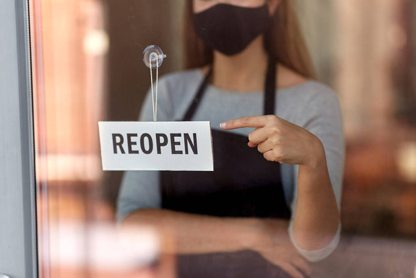 woman in mask with reopen banner on door glass - Foto, Imagem