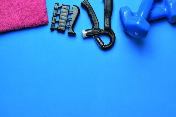 Manual training grip, dumbbells and various accessories, on a blue background. Zenith view and copy space. - Photo, Image