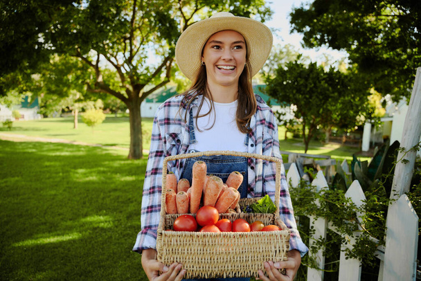 Caucasian female farmer walking outdoors with basket fo fresh vegetables  - Zdjęcie, obraz