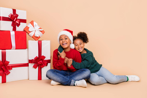 Photo of two people kids embrace enjoy christmas presents wear x-mas hat jumper isolated beige color background - 写真・画像