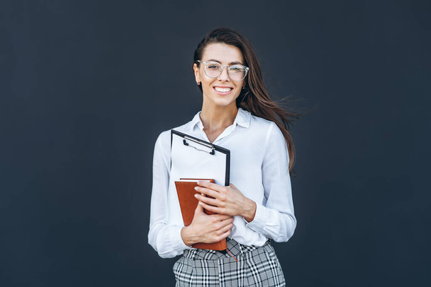 Jonge zakenvrouw met koffie en notebook op grijze achtergrond - Foto, afbeelding