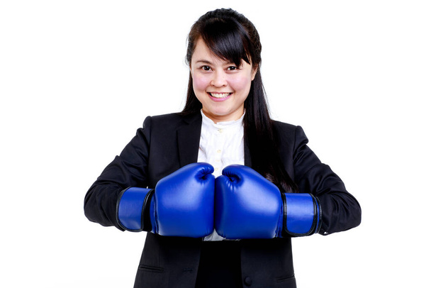Determinato sorridente giovane dirigente asiatica donna in abito formale e guanti da boxe blu guardando la fotocamera con fiducia su sfondo bianco. - Foto, immagini