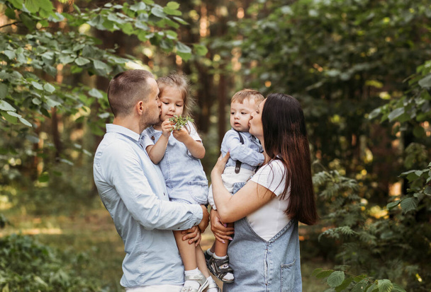 Jovem família feliz com duas crianças na natureza no passeio de verão. Saudável Sorrindo pai, mãe e filhos juntos - Foto, Imagem